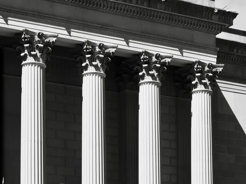 Four fluted stone columns on the facade of a classical public building, in black and white