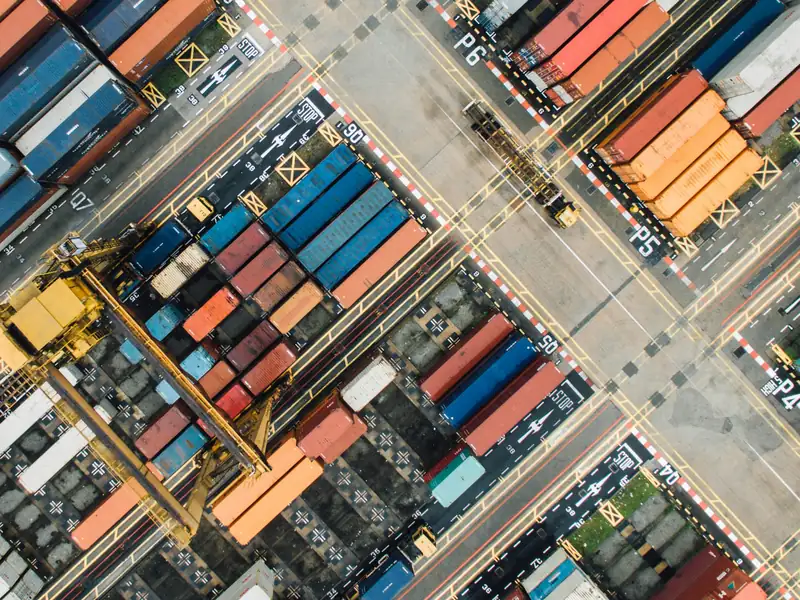 Aerial view of stacked shipping containers, lanes and a gantry crane in a container yard