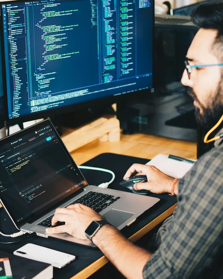 A developer working with code on a laptop and a second monitor