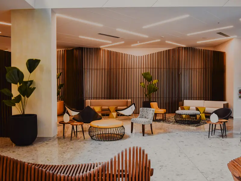 A modern hotel lobby with armchairs, low tables and a wooden slatted wall
