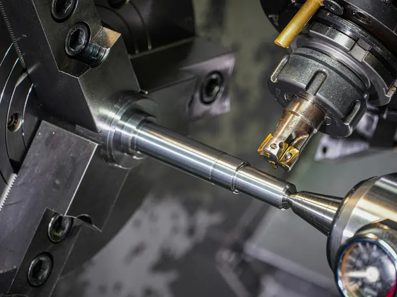 A steel rod being machined on a lathe by a milling cutter